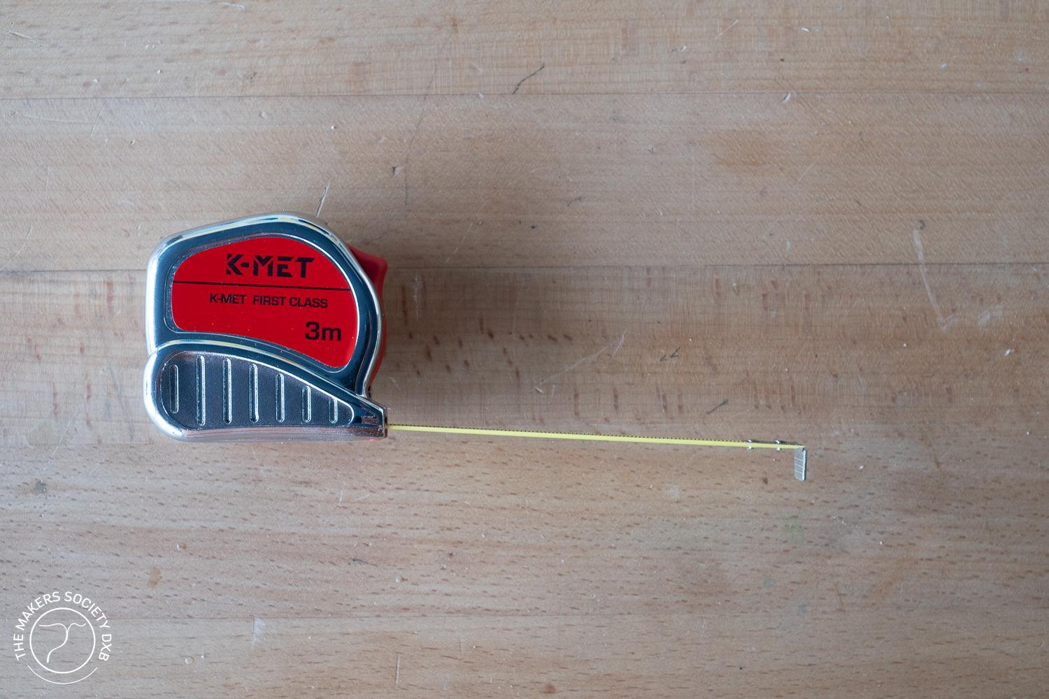 K-MET First Class 3m tape measure with red and silver casing on wooden surface