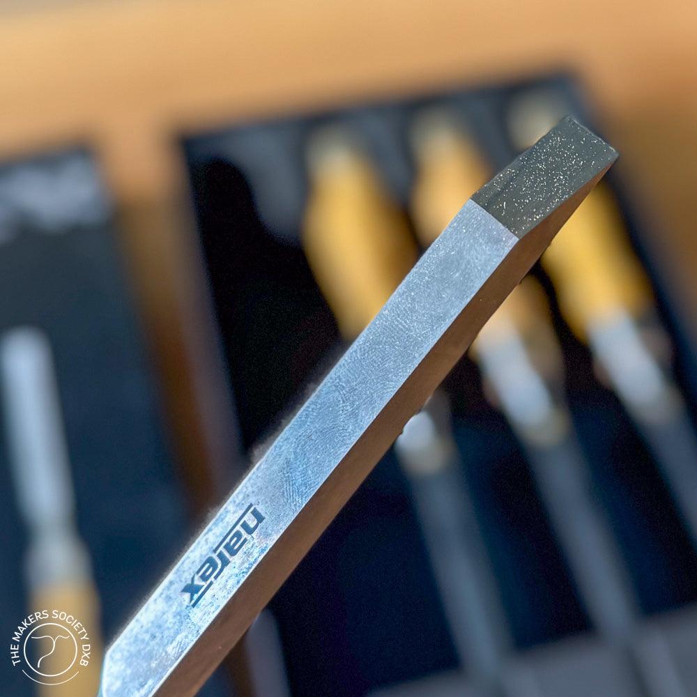 Close-up of Narex mortise chisel steel blade with wooden handles in the background set on black tray