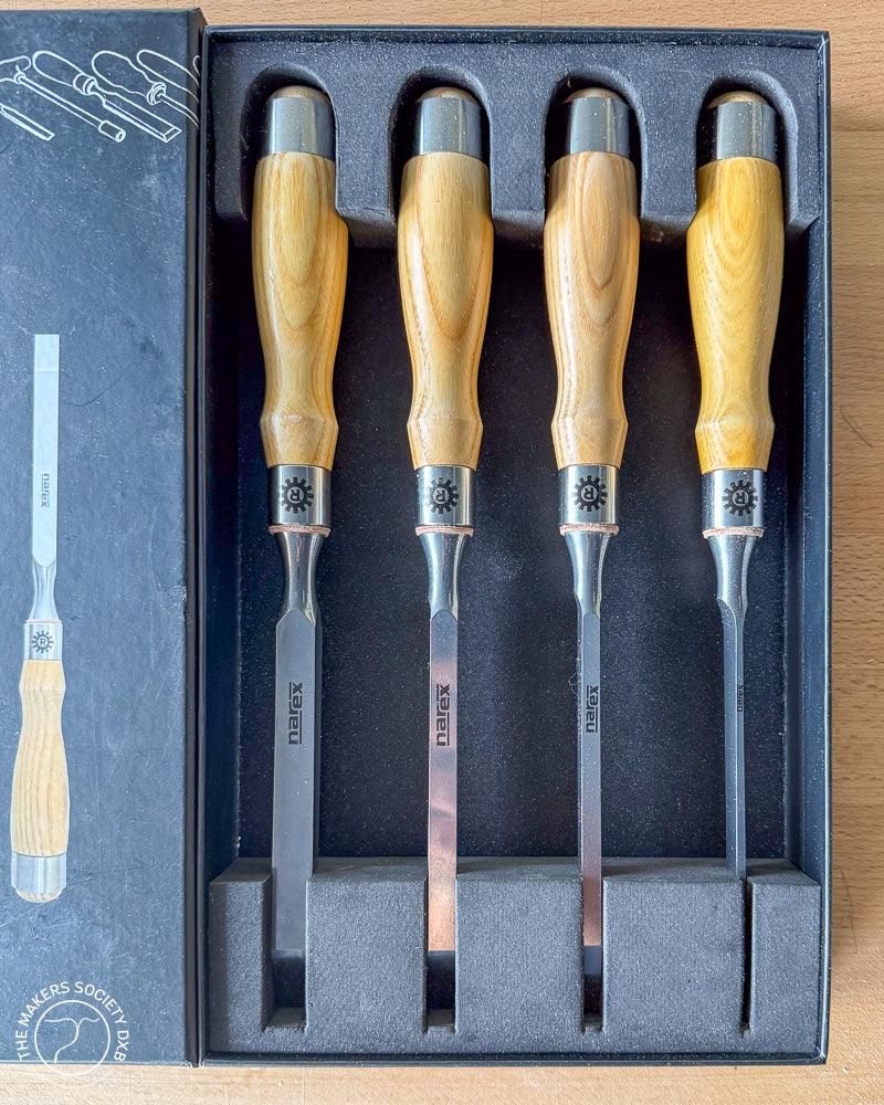 Set of four Narex mortise chisels with wooden handles in black foam packaging, displayed on wooden surface