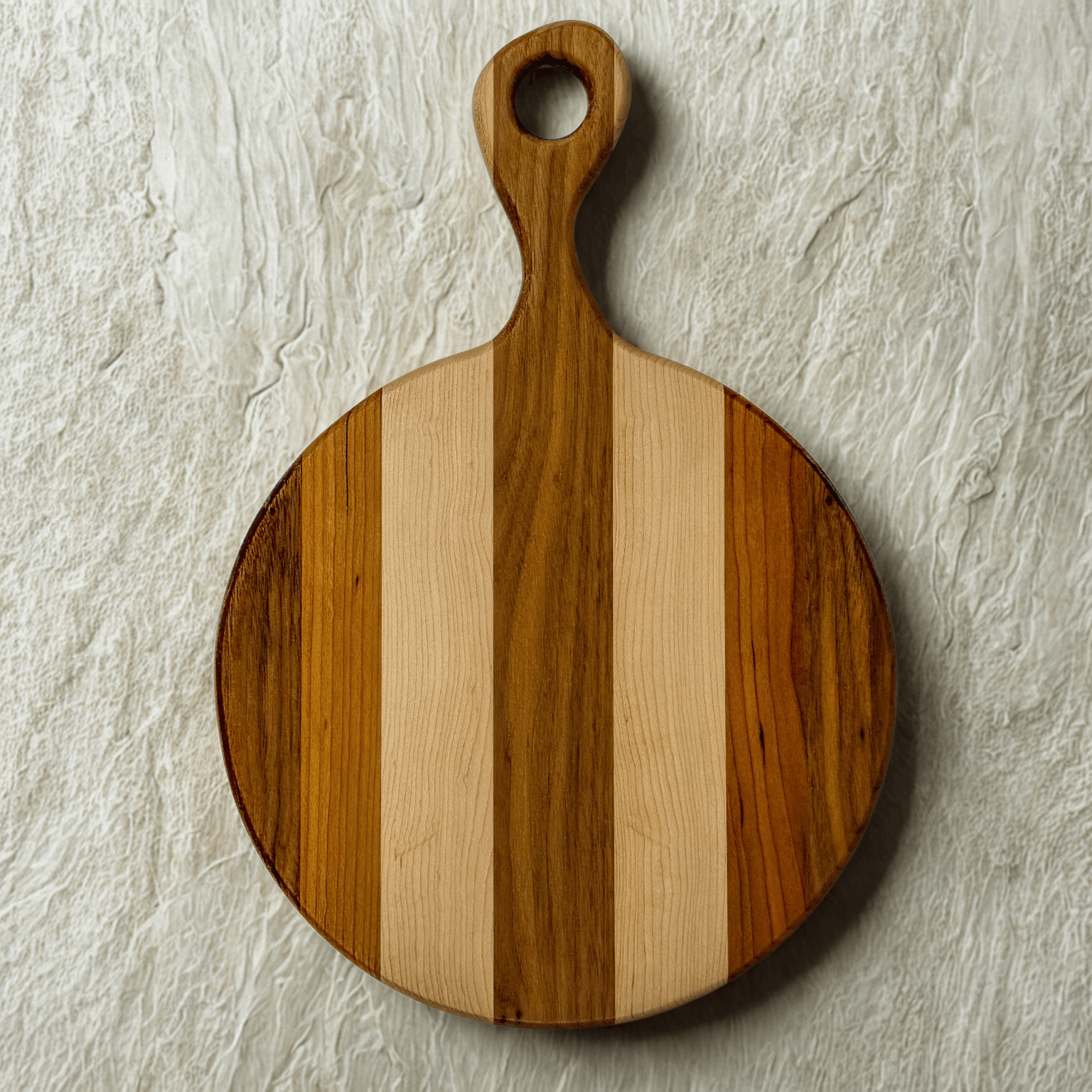 artisan striped round wooden cutting board with handle on textured white surface