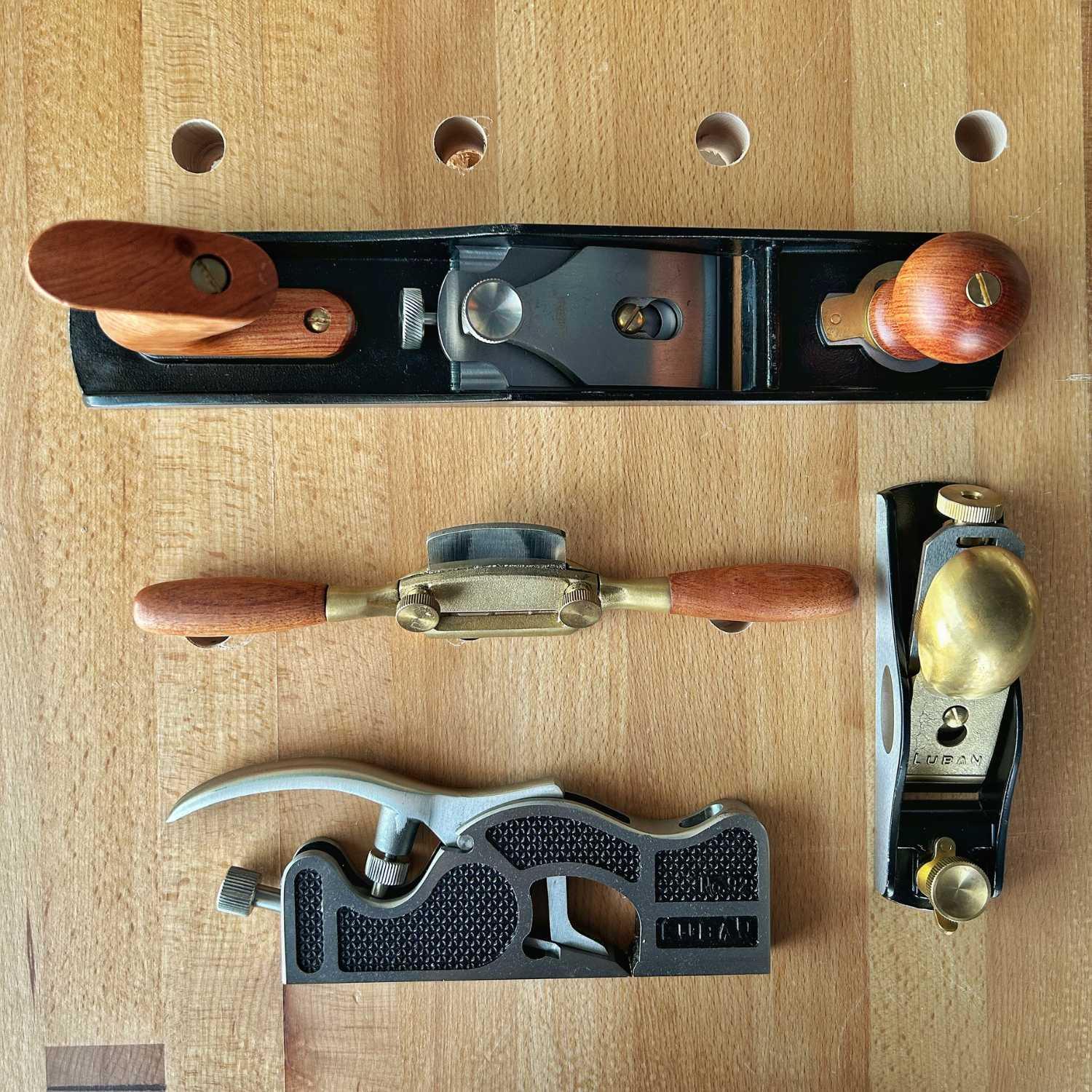Set of four woodworking planes with wooden handles on a wooden workbench surface