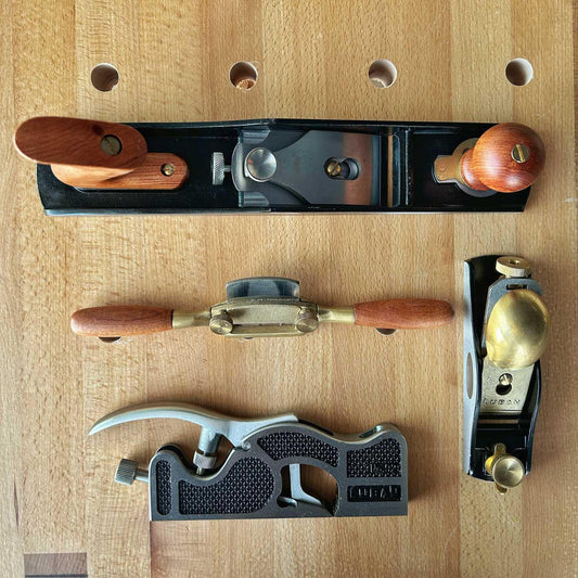 Set of four woodworking planes with wooden handles on a wooden workbench surface