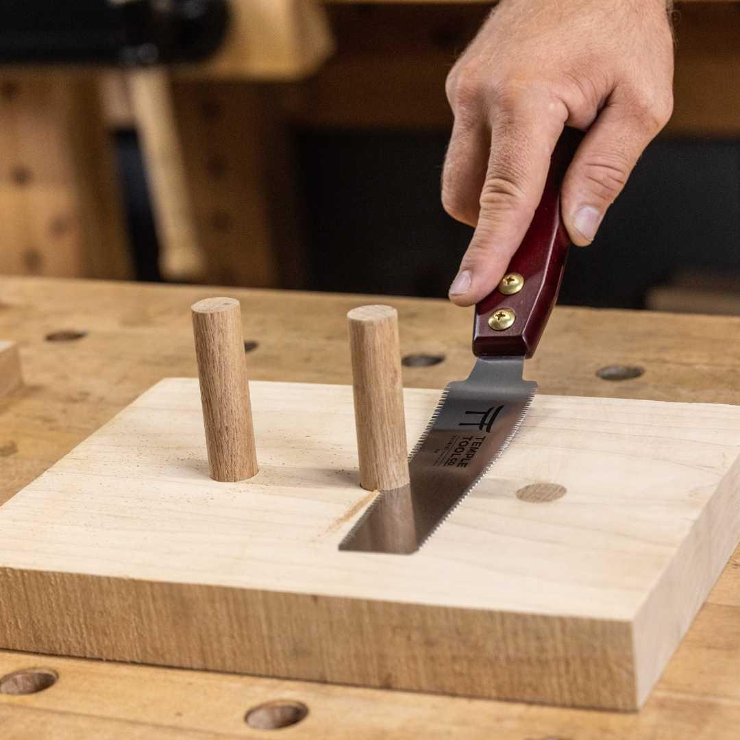 Hand cutting wood dowels with a Temple Tool flush cut pull saw on a wooden workbench