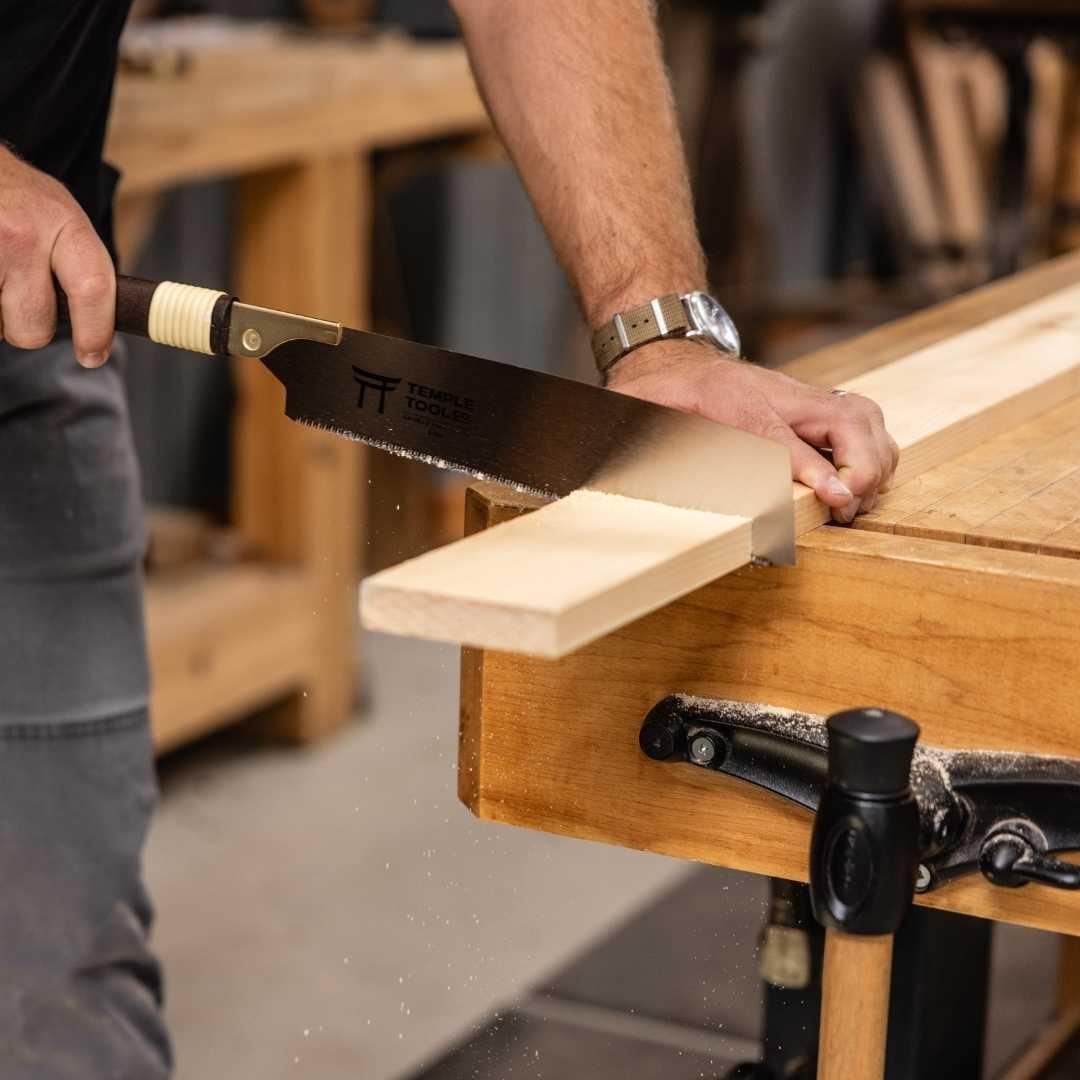 Person using Temple Tools Kataba pull saw to cut wood on a woodworking bench