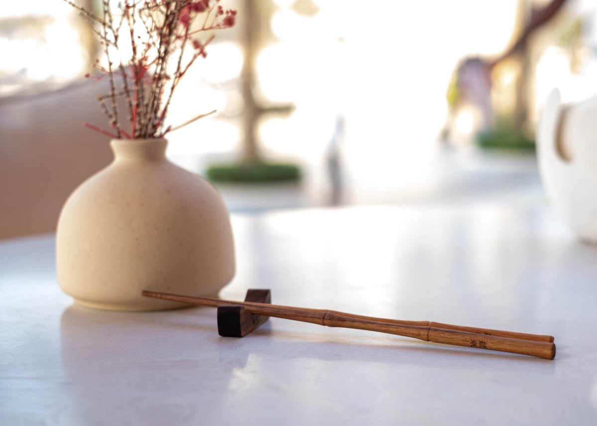 Finished pair of handmade wooden chopsticks on a walnut rest, the shape a class piece works towards