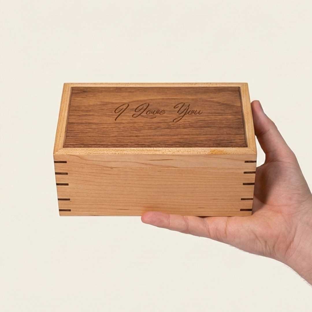 Wooden box with 'I Love You' engraving held by a hand on a beige background