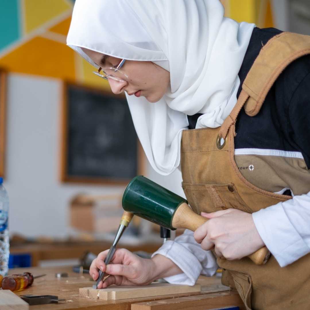 Woman in workshop using woodworking tools and chisel, makerspace Dubai community class