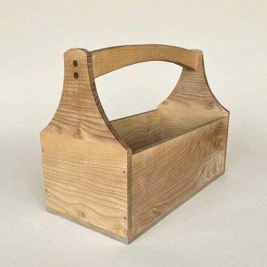 A professional studio shot of a handcrafted ash wood toolbox shown from a 3/4 angle, featuring natural grain patterns and a minimalist design on a warm off-white background.