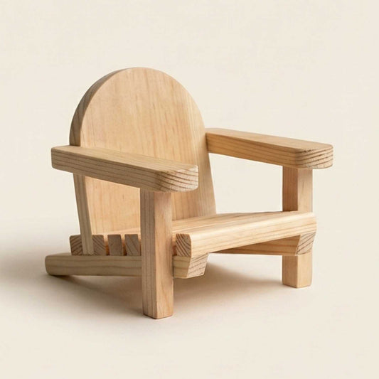A handcrafted miniature wooden Adirondack chair featuring a rounded backrest and slatted seat, displayed at a three-quarter angle on a clean, warm off-white studio background.