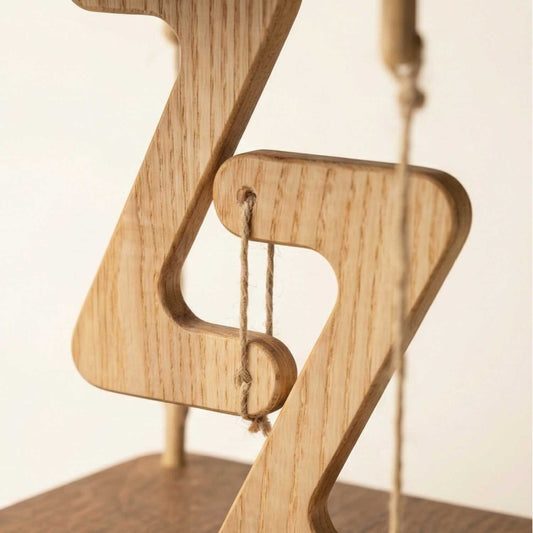 Wooden music note sculpture with a string on a light background