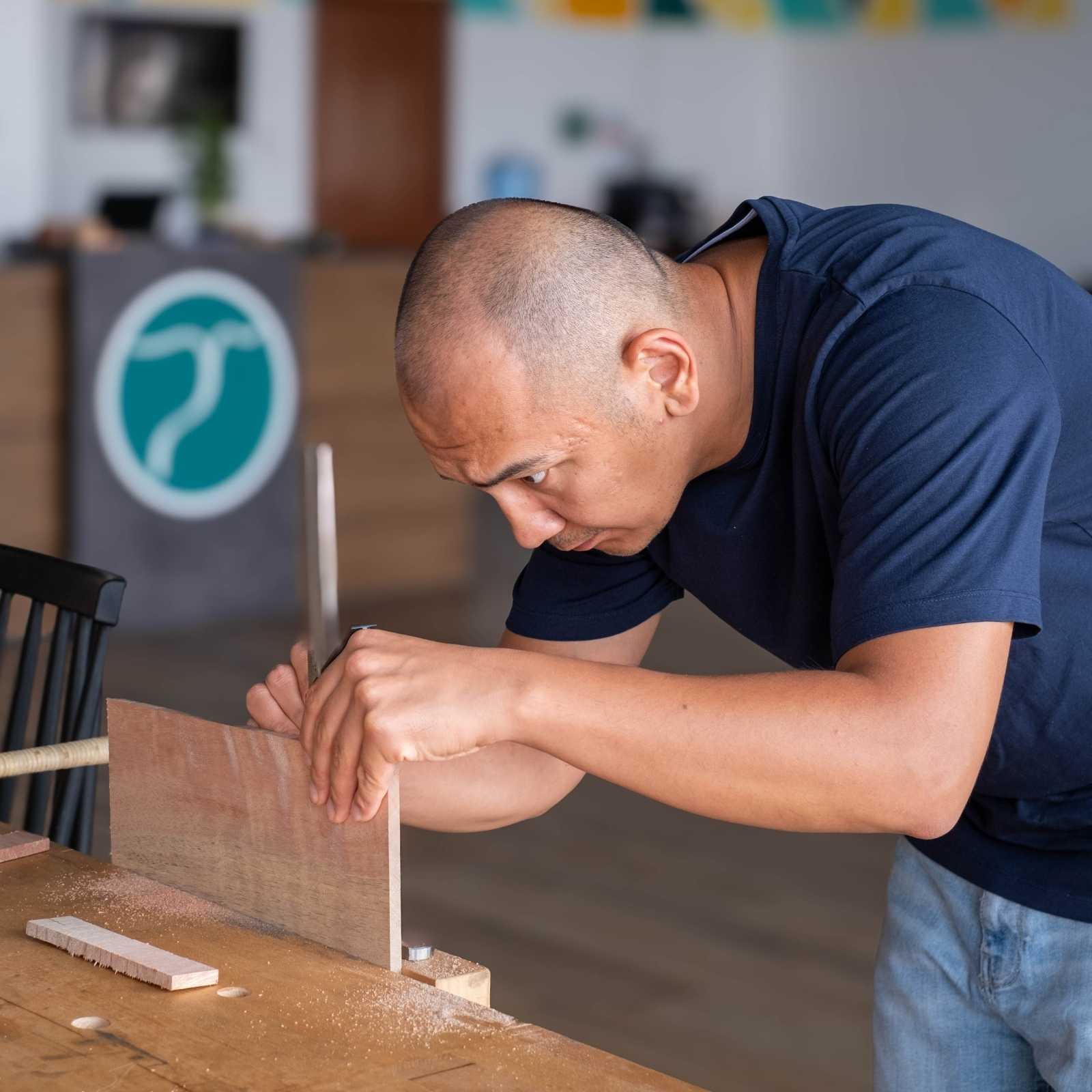 Maker using hand tools at a woodworking bench inside The Makers Society workshop in Dubai