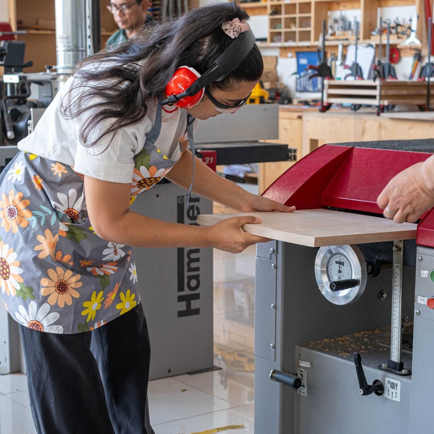 A student of The Makers Society Dubai is feeding a board of soft maple into a thicknesser