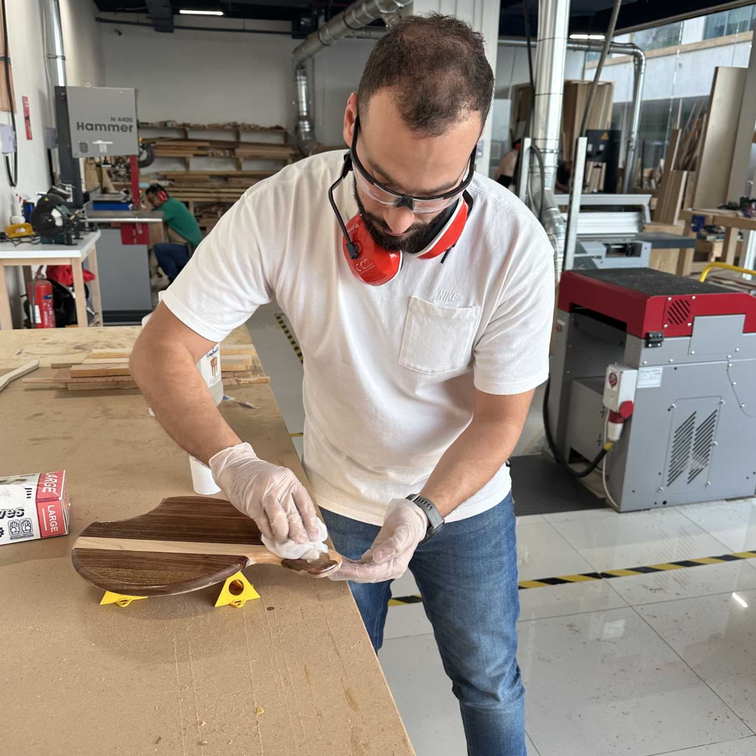 Student at The Makers Society applying finish to a wooden board in a workshop
