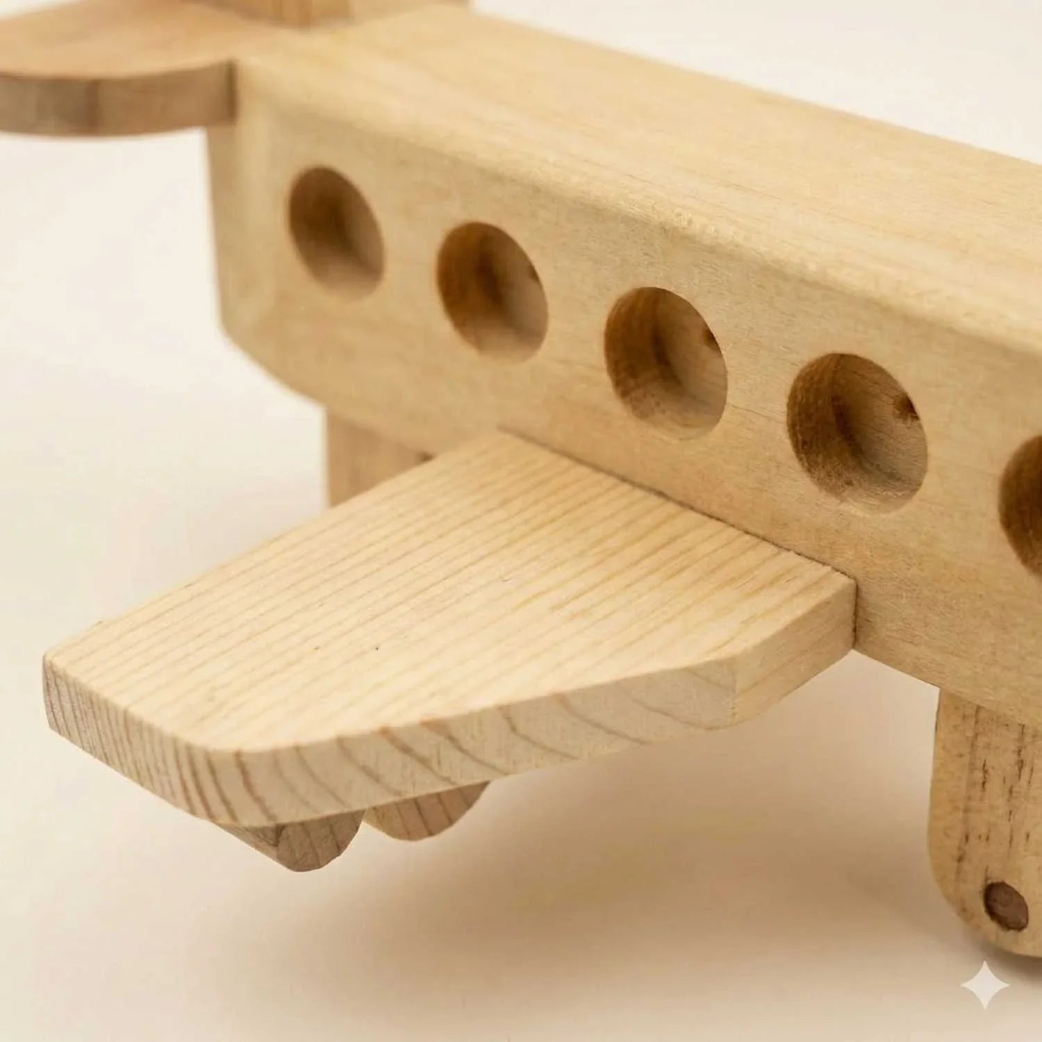 Macro close-up shot of a wooden toy airplane highlighting the intricate natural wood grain patterns and the precise joinery of the wing and fuselage.