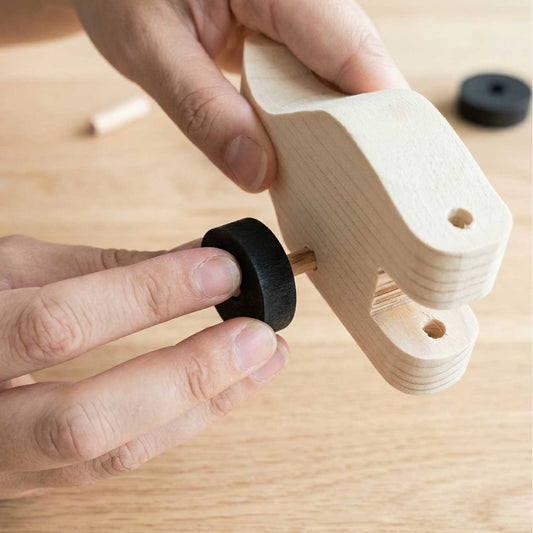 Attaching a wooden wheel to a puppy pull-along from The Makers Society kids woodworking kit