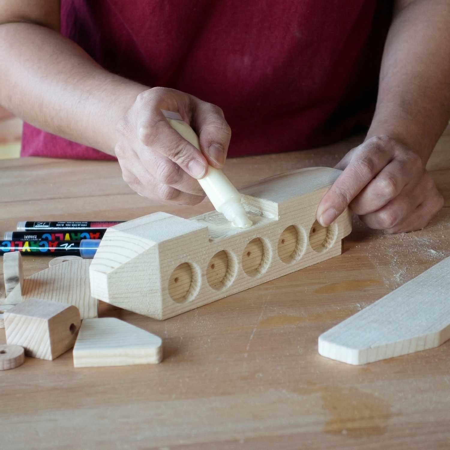 Applying wood glue to a wooden aeroplane from The Makers Society kids woodworking kit during assembly