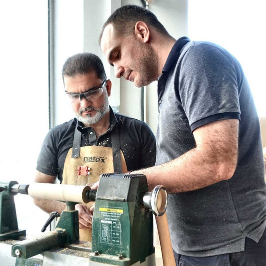 Instructor guiding a student at a wood lathe during a woodturning trial class at The Makers Society in Dubai.